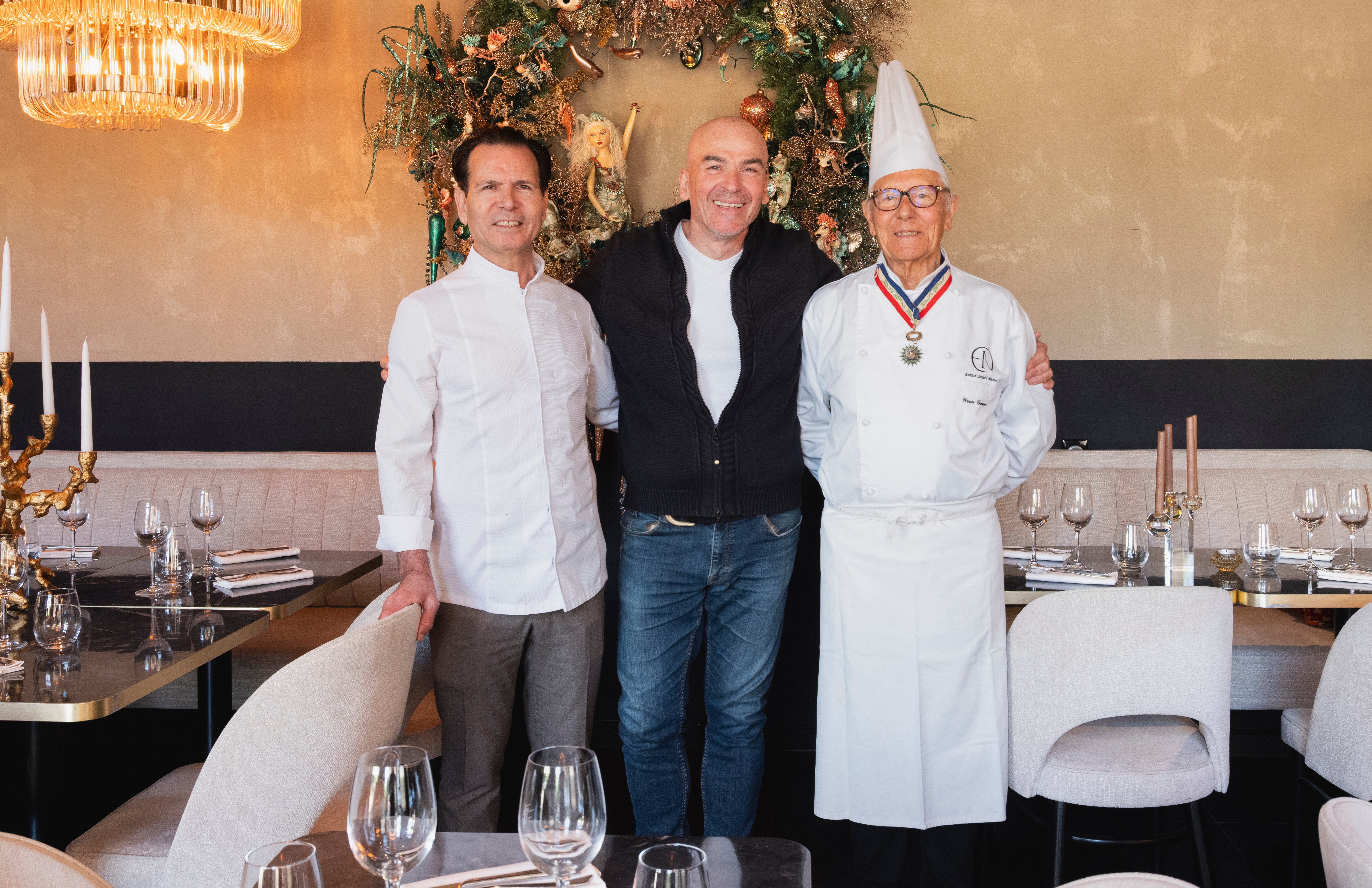 Three chefs posing for a photo in a restaurant.