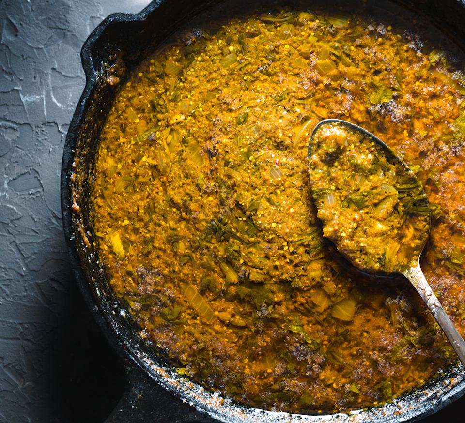 Hearty dish in a cast iron skillet with a ladle resting inside, featuring a textured, thick, stew-like consistency