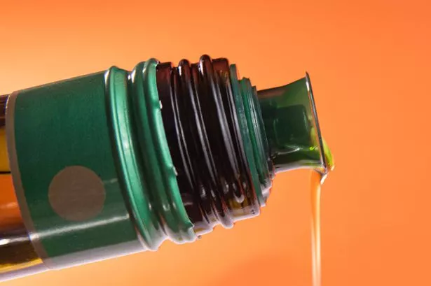 Olive oil container over orange background