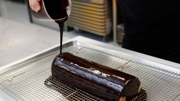 Pastry chef Clément Le Déoré of Desserts by Clément puts a glaze on a bûche de Noël on Tuesday, Nov. 19, 2024. (K.C. Alfred / The San Diego Union-Tribune)
