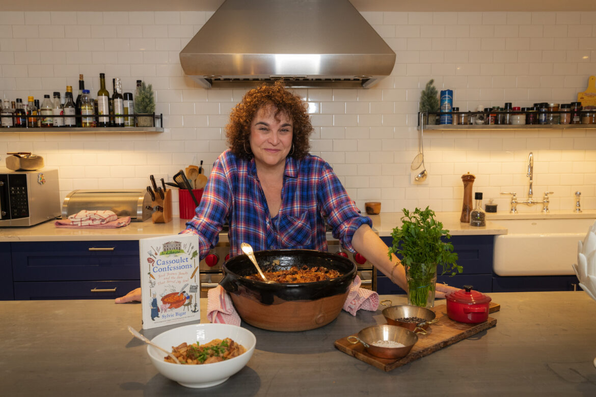 Sylvie Bigar in the kitchen with her book “Cassoulet Confessions: Food, France, Family and the Stew That Saved My Soul