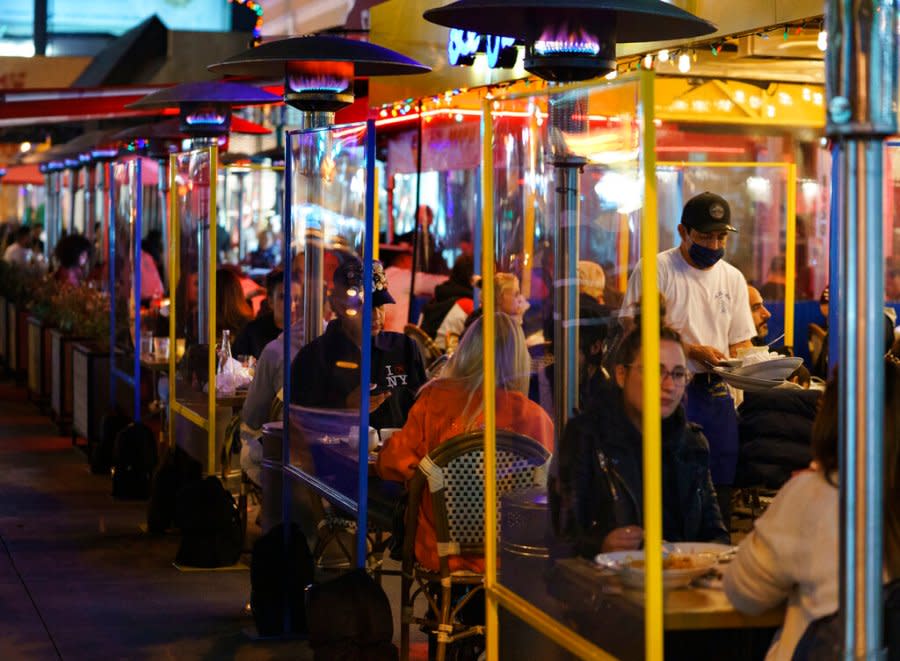 Patrons eat under a row of gas heaters as they seat outdoors on the curbside at Le Petit Four French restaurant at Sunset Plaza on Sunset Blvd., in West Los Angeles late Nov. 24, 2020. (AP Photo/Damian Dovarganes)