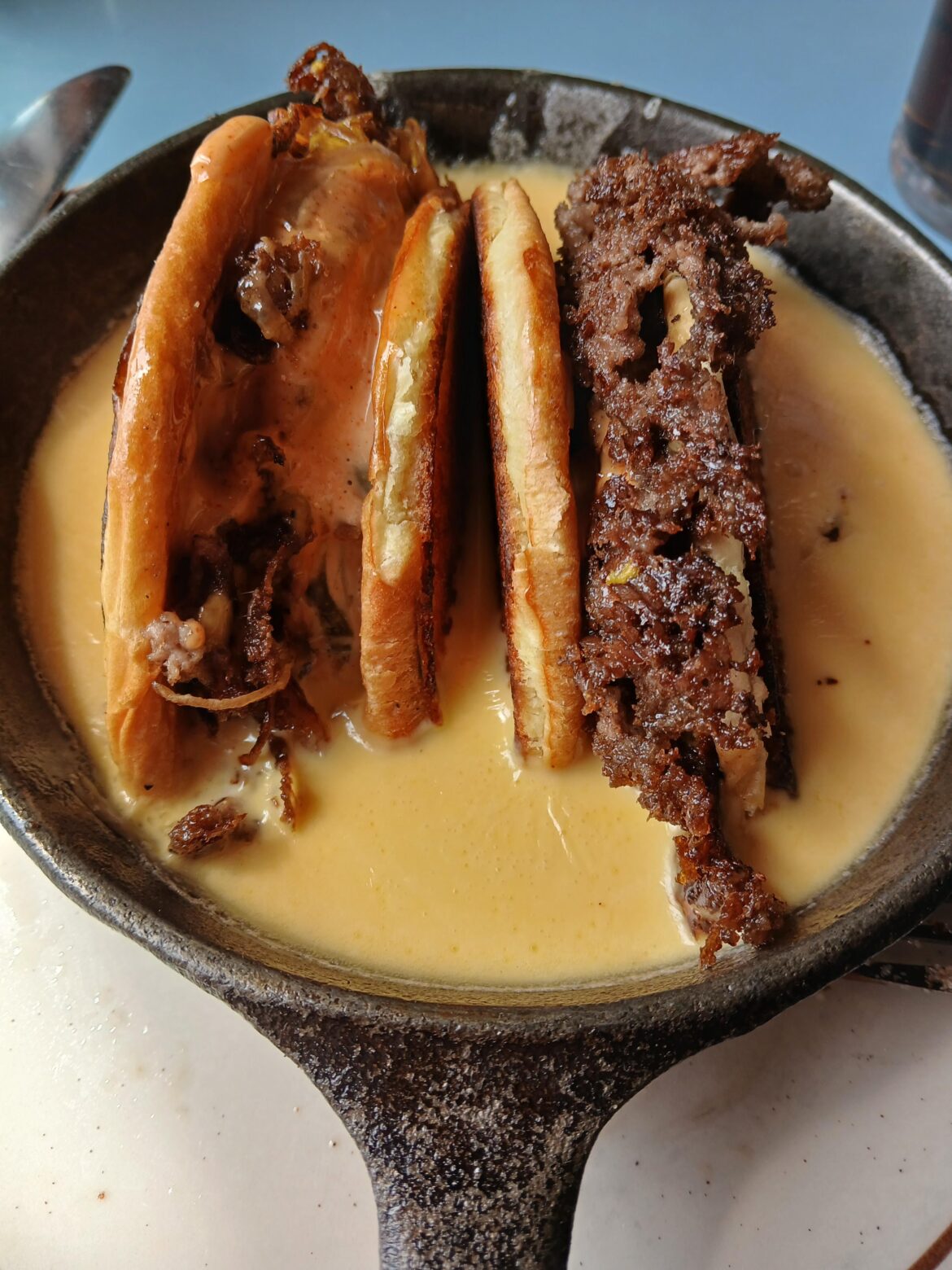 Smash burger in half face down in bechamel cheese sauce