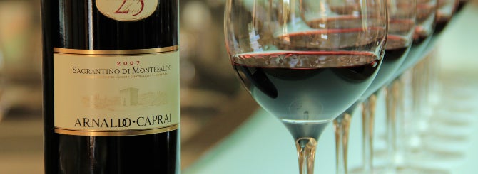 A bottle of Sagrantino with glasses of the same beside it.