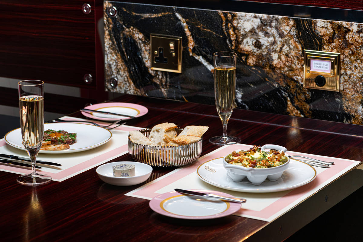 a table set with food and glasses of champagne with a marble backsplash and a 'press for champagne' button