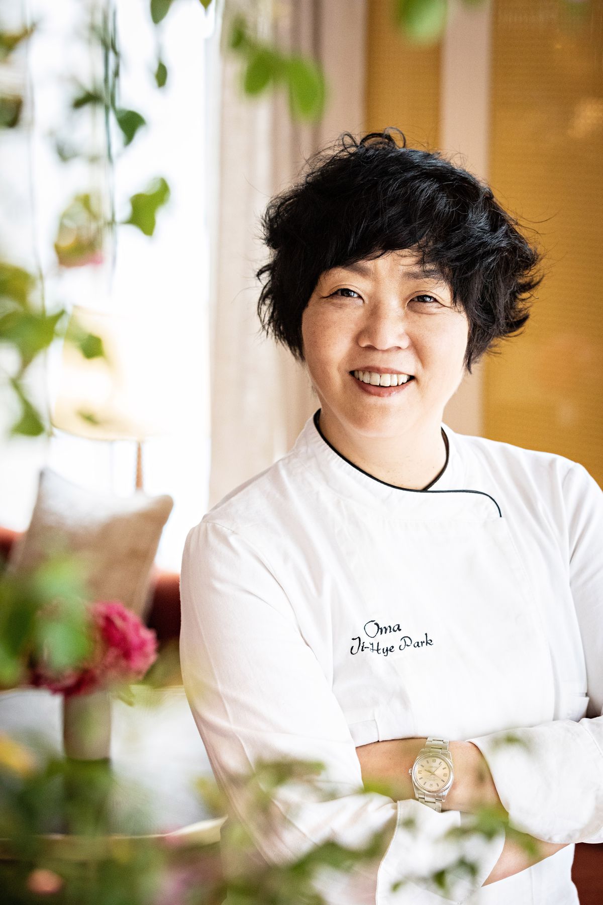 A chef stands with her arms crossed in chef whites.