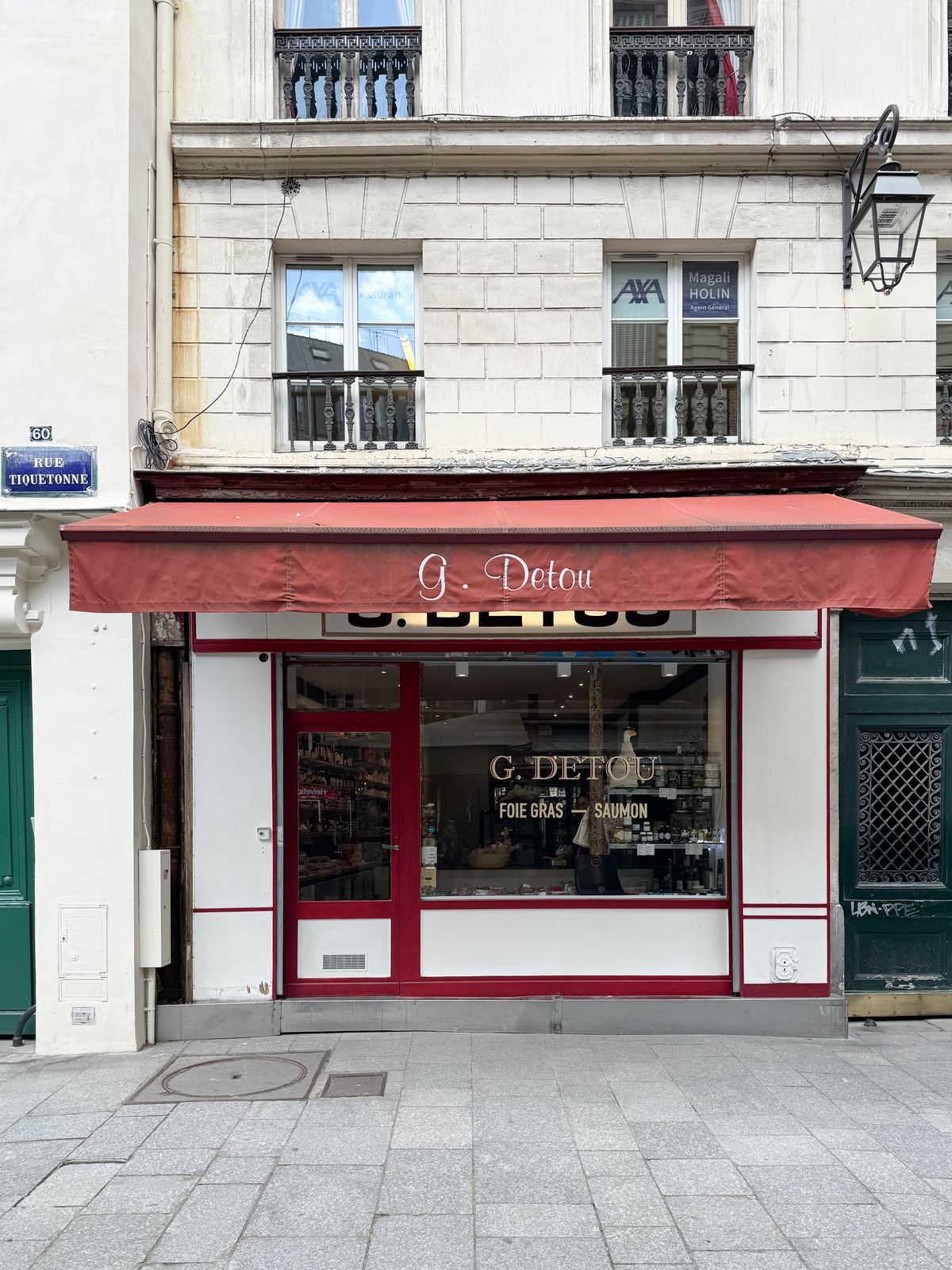 A Parisian storefront with awning and glass window. 