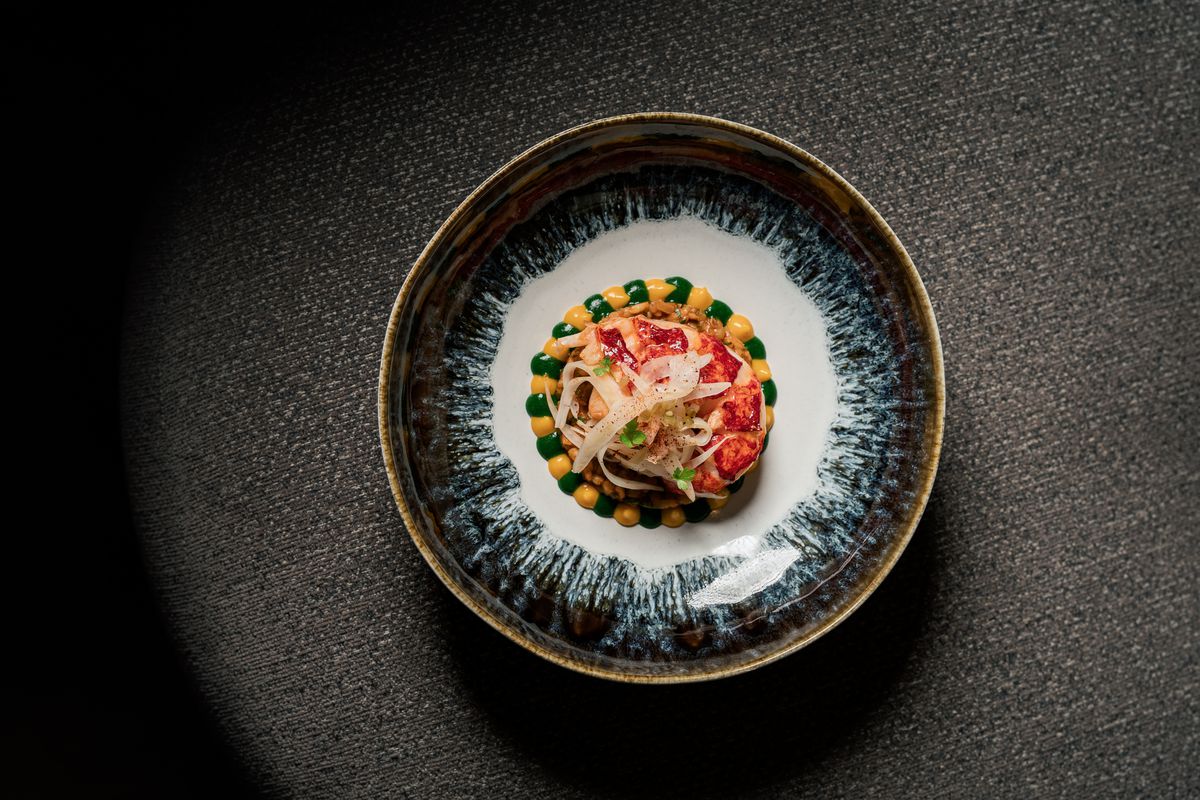 A top-down view of a colorful lobster dish on a black background.