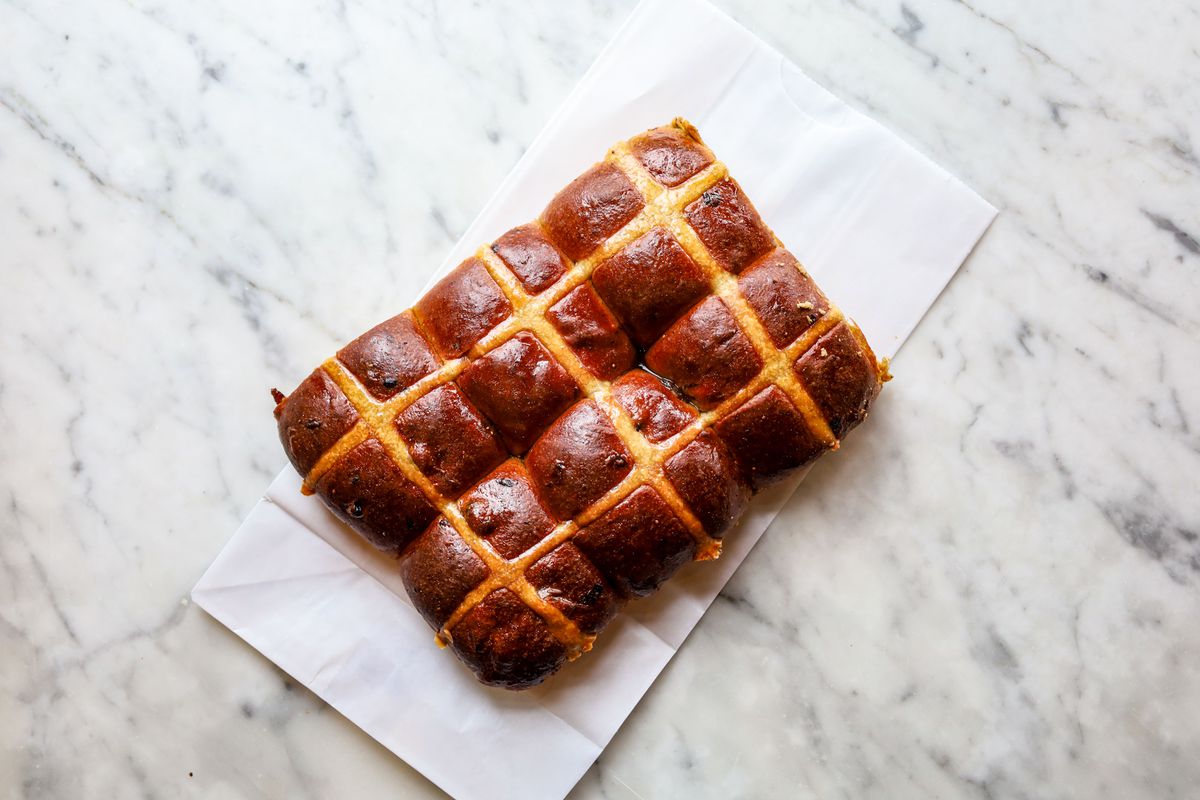 Buns with a cross in the middle on a marble countertop.