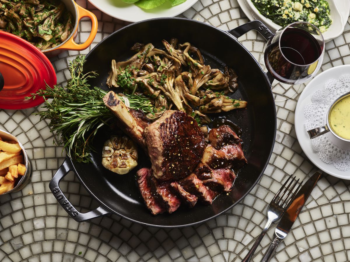 Sliced beef garnished with herbs sits in a black pan.