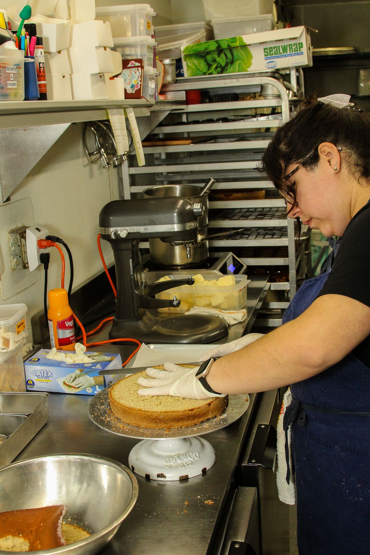 Pino slices a cake in half, with butter being softened for frosting on the side