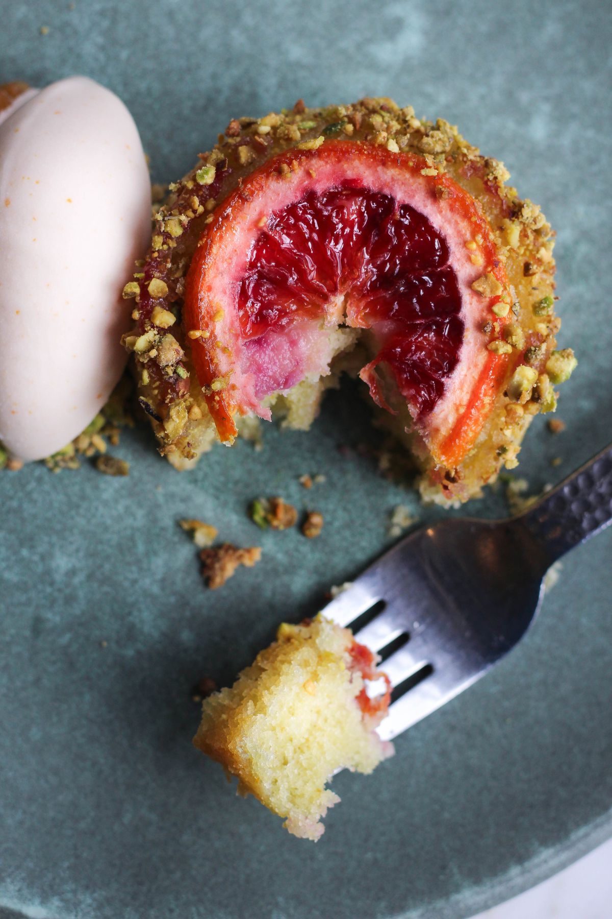 A cake topped with blood orange with a bite taken out of it
