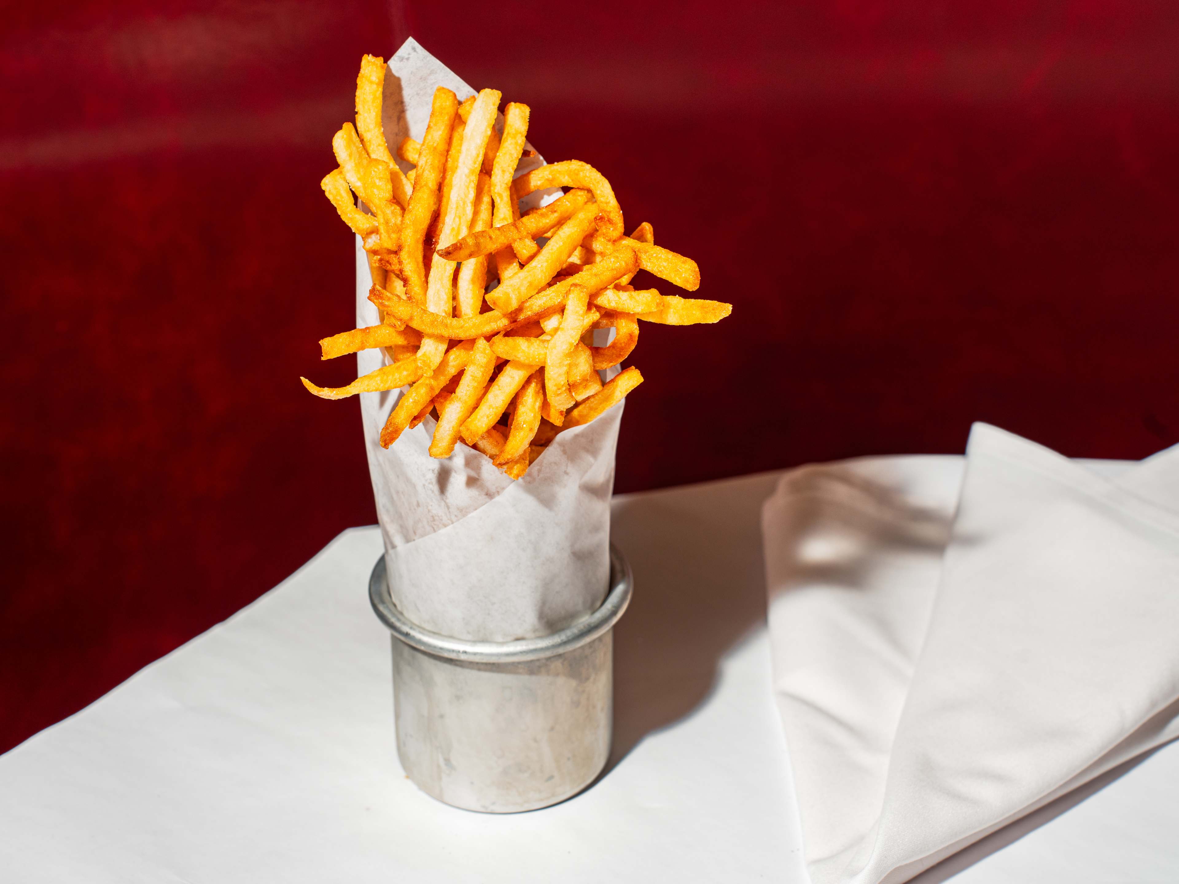 french fries spilling over the paper cone inside a metal canister