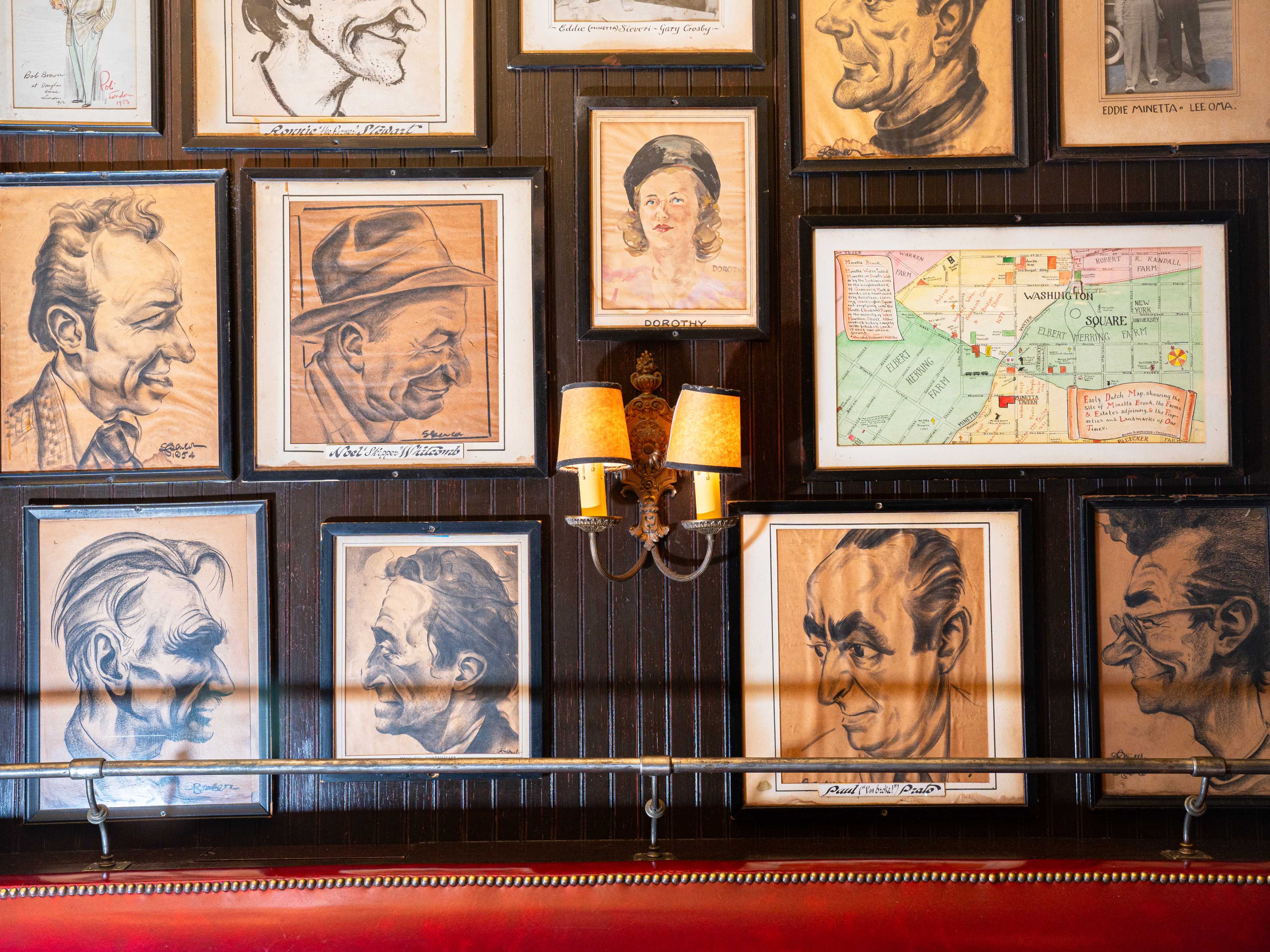 wall of caricatures around two lamps and a map of the area with Minetta Tavern marked on it