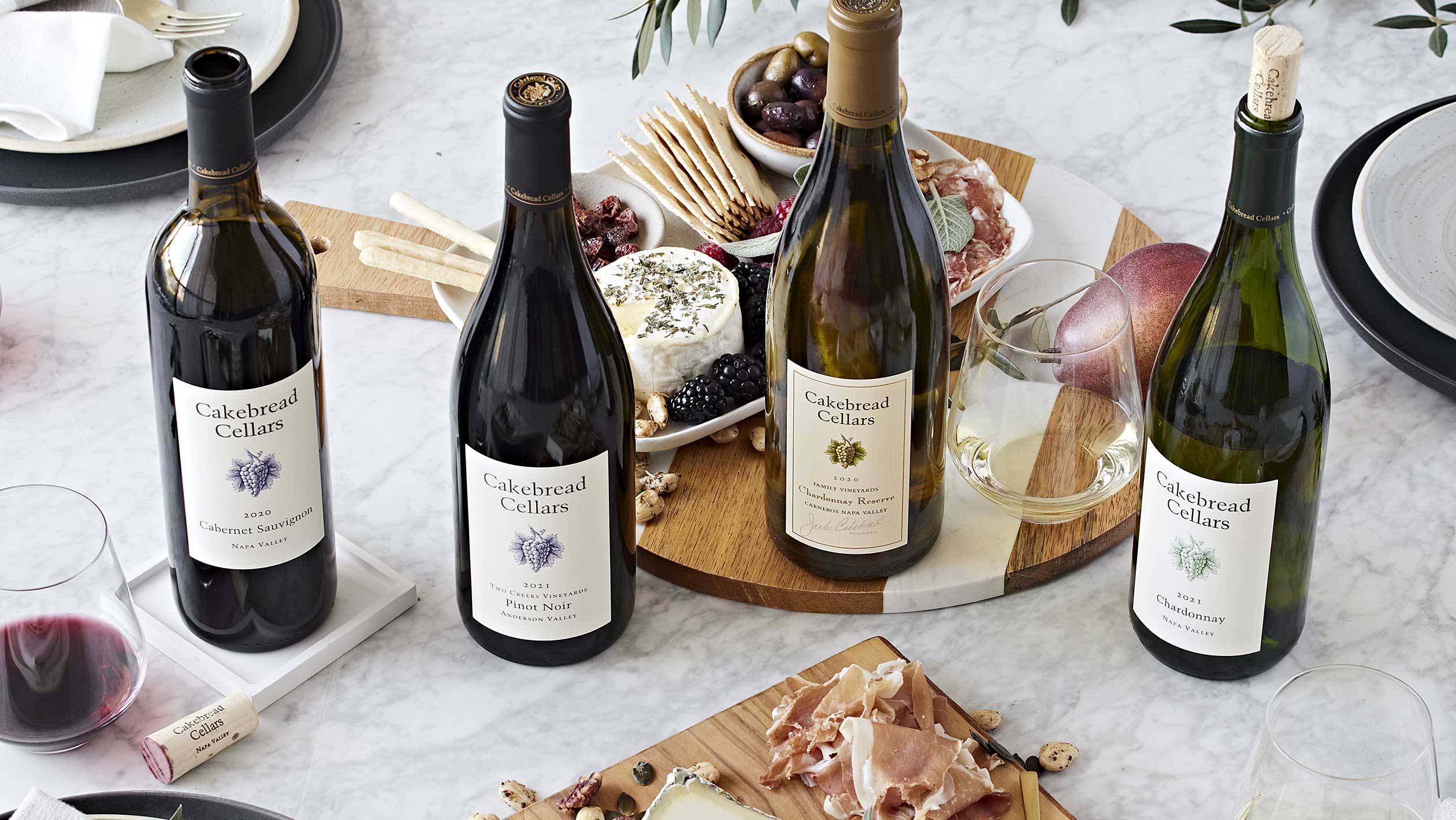 Four bottles of Cakebread next to a charcuterie board