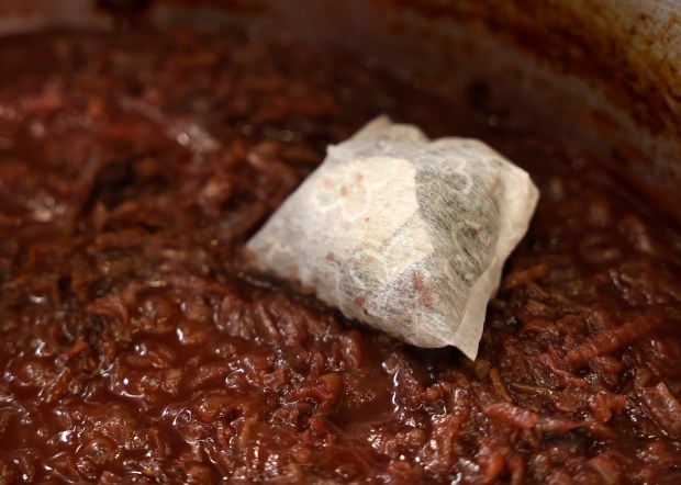 An herb pouch is added to caramelized onions during the...