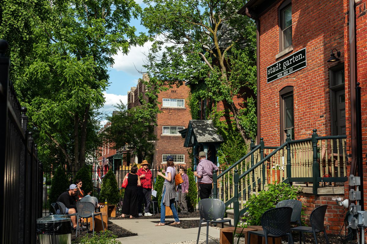 A small crowd of people mingling on an outdoor patio at Stadt Garten in Midtown Detroit.