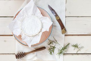 Camembert, rosemary, knife, honey dipper, preparation for baked camembert