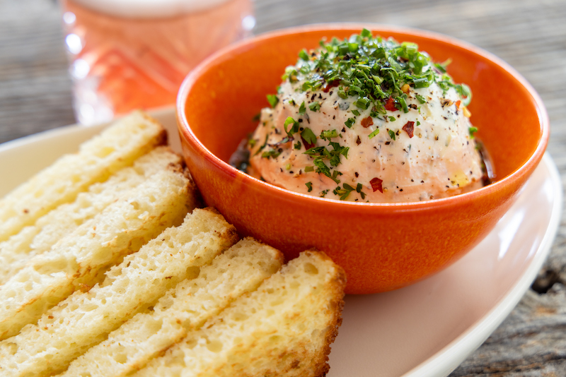 This photo shows a bowl of whipped herb ricotta with five pieces of focaccia bread