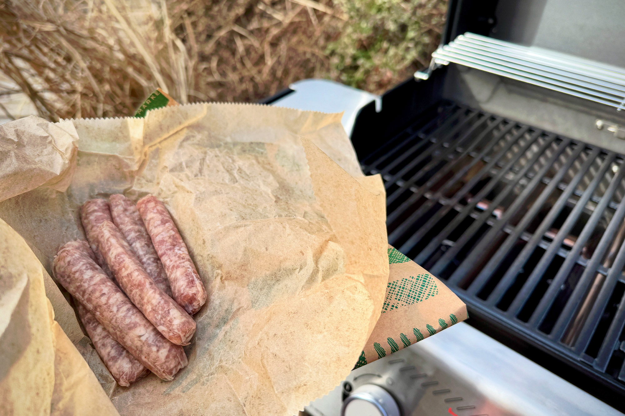 Raw sausages held over the Weber Spirit Propane Grill just before grilling