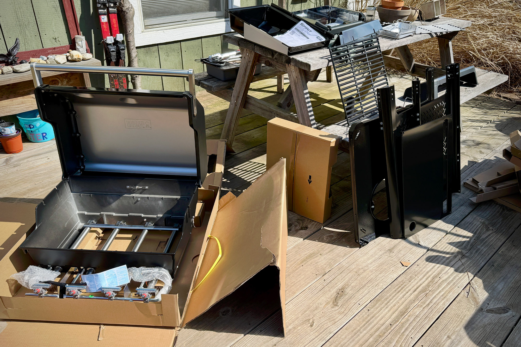 Unboxed parts of the Weber Spirit Propane Grill laid out on a wooden deck before assembly