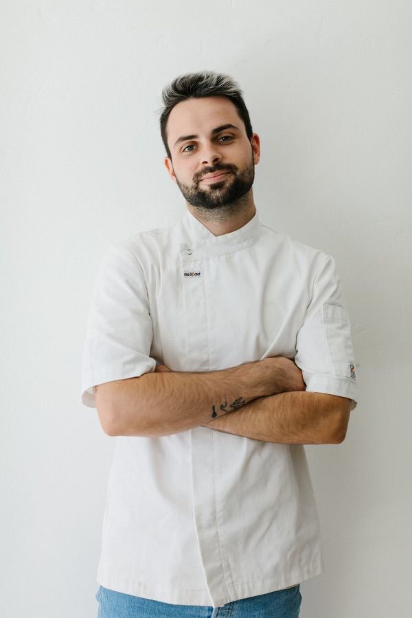 A chef stands with his arms crossed. 
