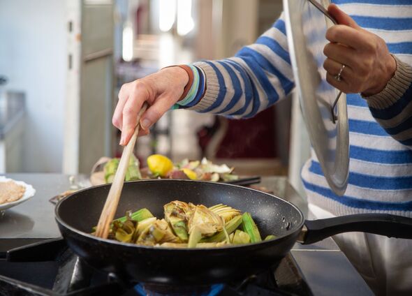 Woman cooking artichokes in frying pan