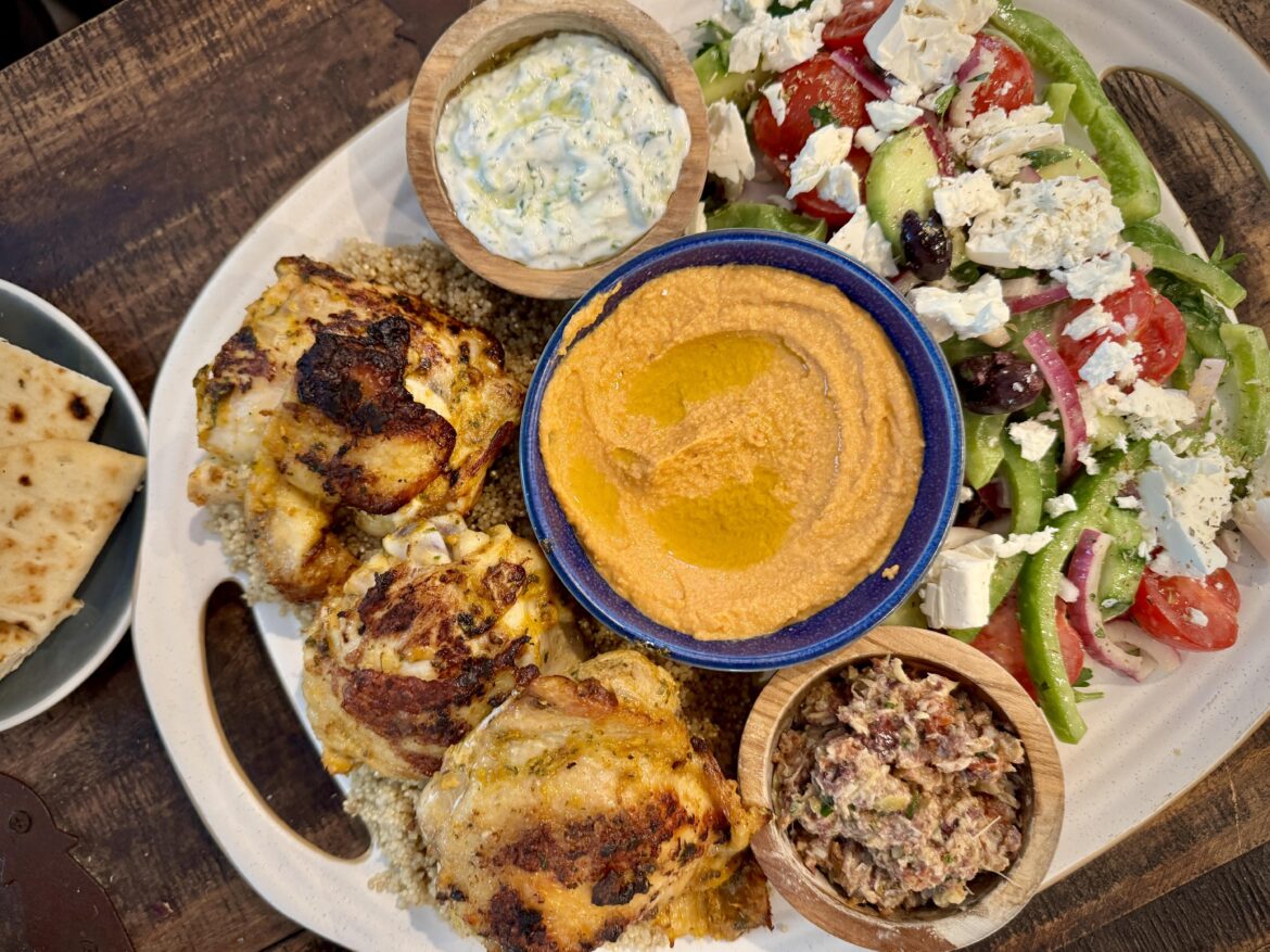 Dijon and herb roasted chicken thighs over quinoa, homemade sun-dried tomato hummus, artichoke-olive tapenade & tzatziki, alongside Greek salad with homemade dressing.