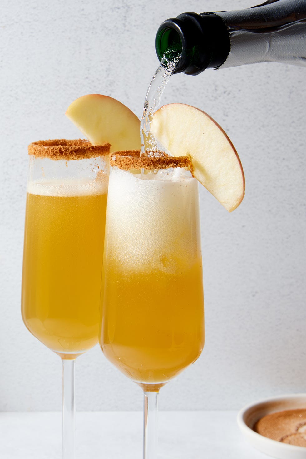 apple cider mimosas with a cinnamon rim and apple slices