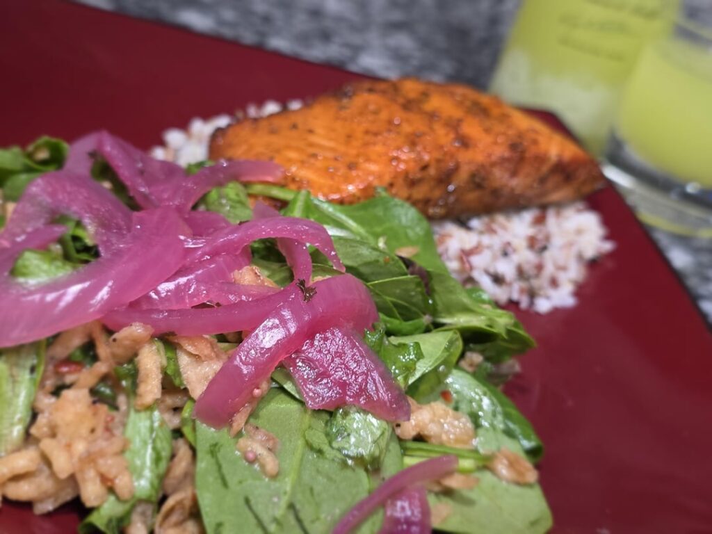 Balsamic honey glazed salmon baked on a cedar plank, on a b3d of wild rice with a spring mix salad, raspberry vinaigrette, crispy fried onions, and pickled red onions