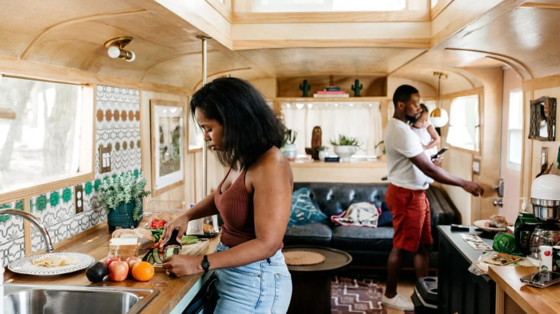 A woman preparing food and a man holding a child.