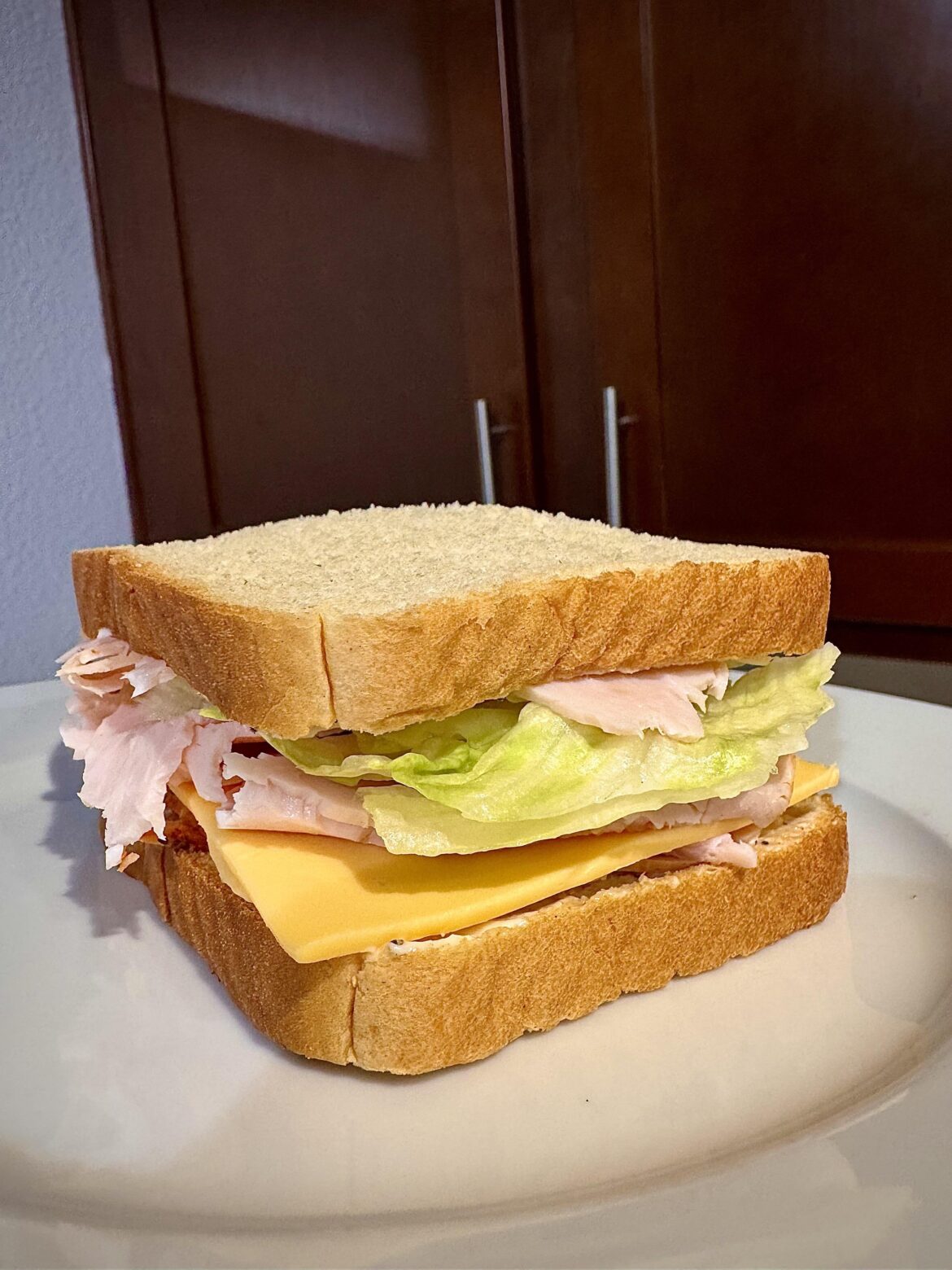 Turkey and American cheese with lettuce, olive oil mayo, and black pepper on white bread