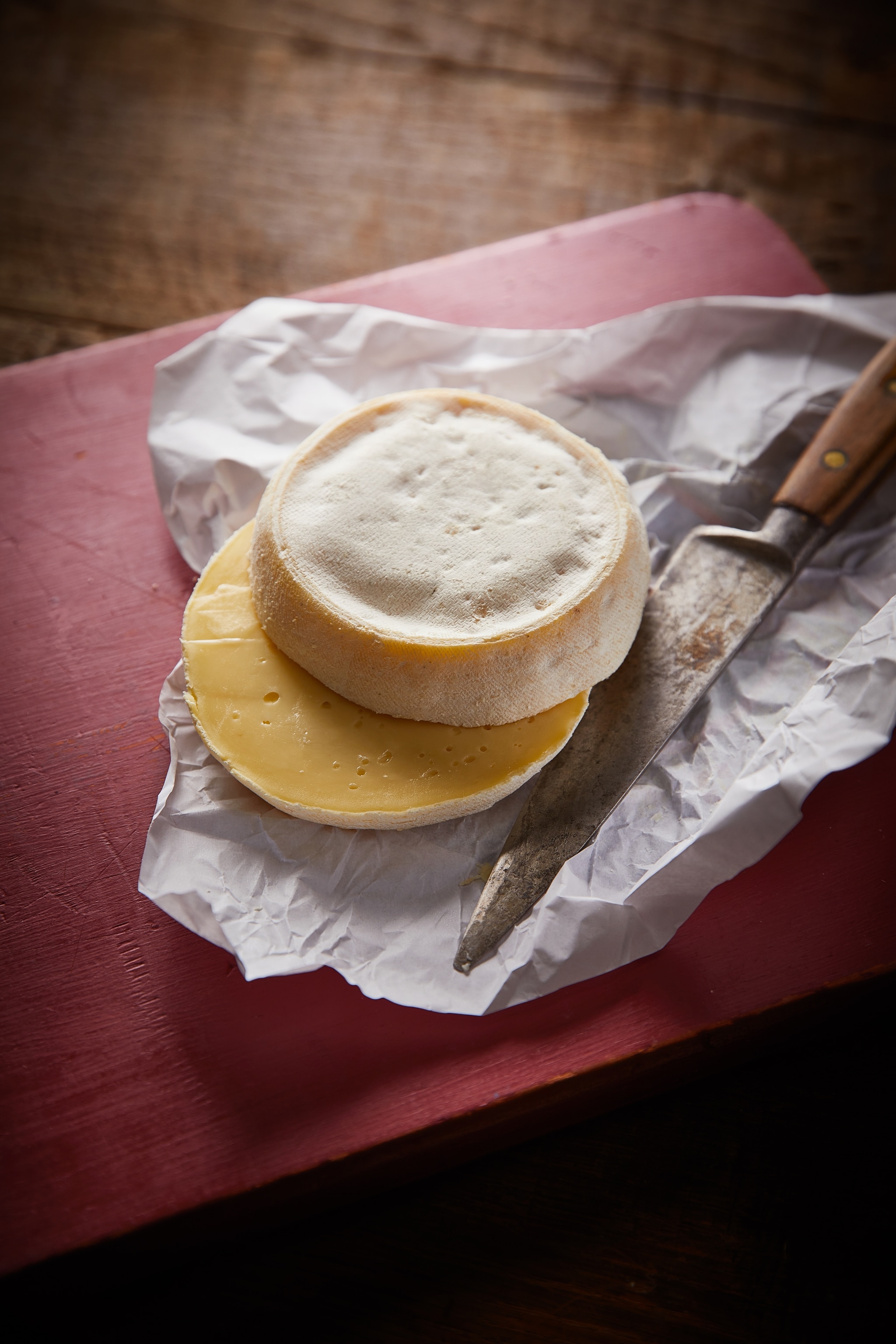 A wheel of reblochon cheese cut in half on top its wrapper