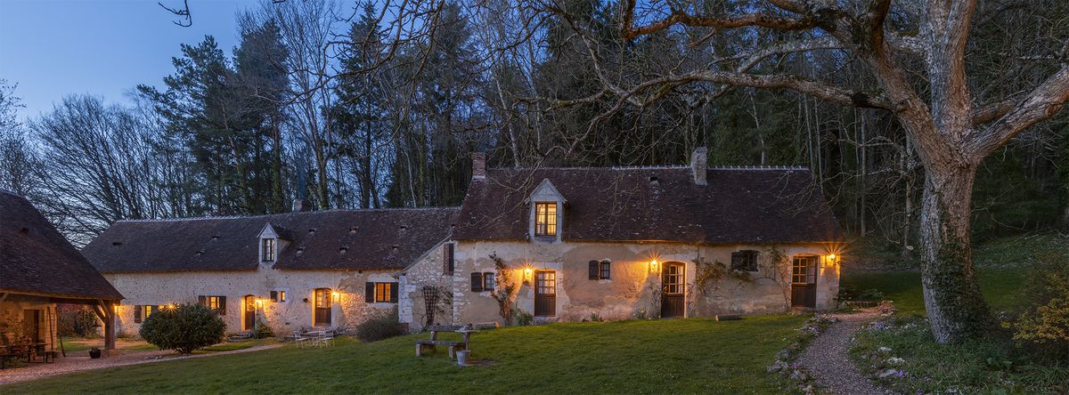 A country inn among the woods lit up in the evening.