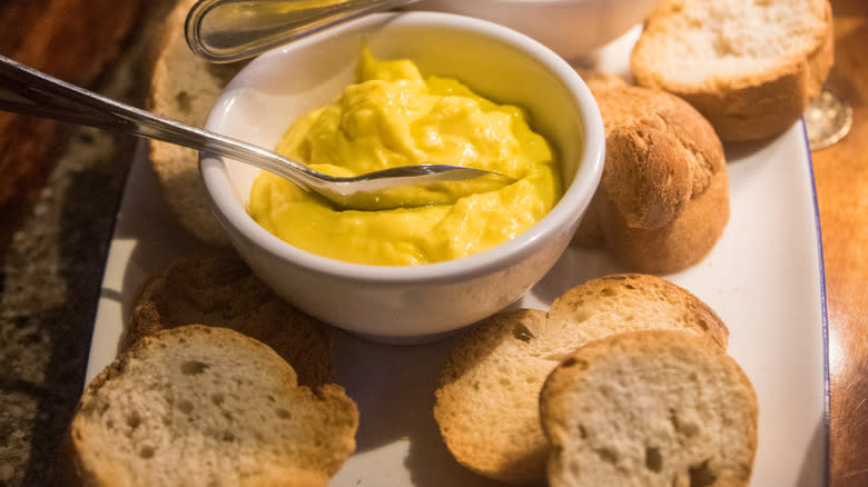 A bowl of rouille sauce, with some baguette.