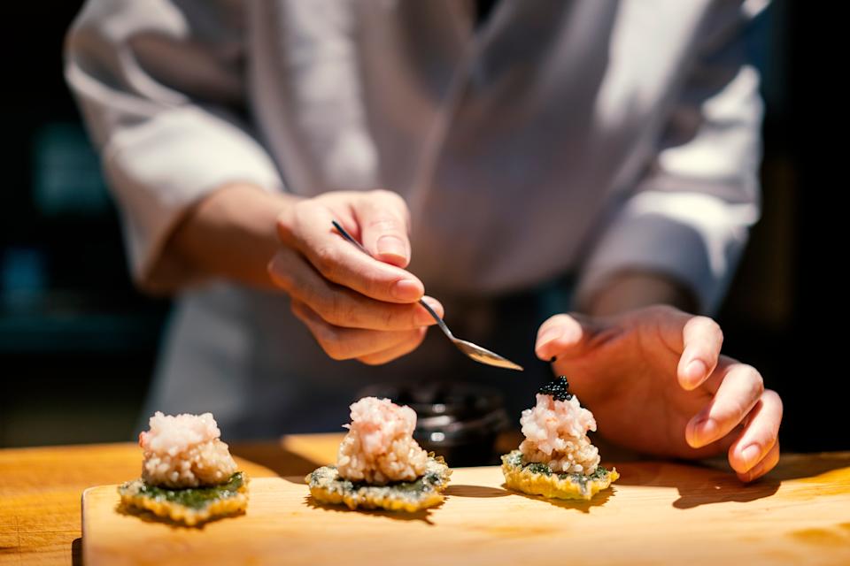 Chef delicately placing caviar on gourmet appetizers in kitchen
