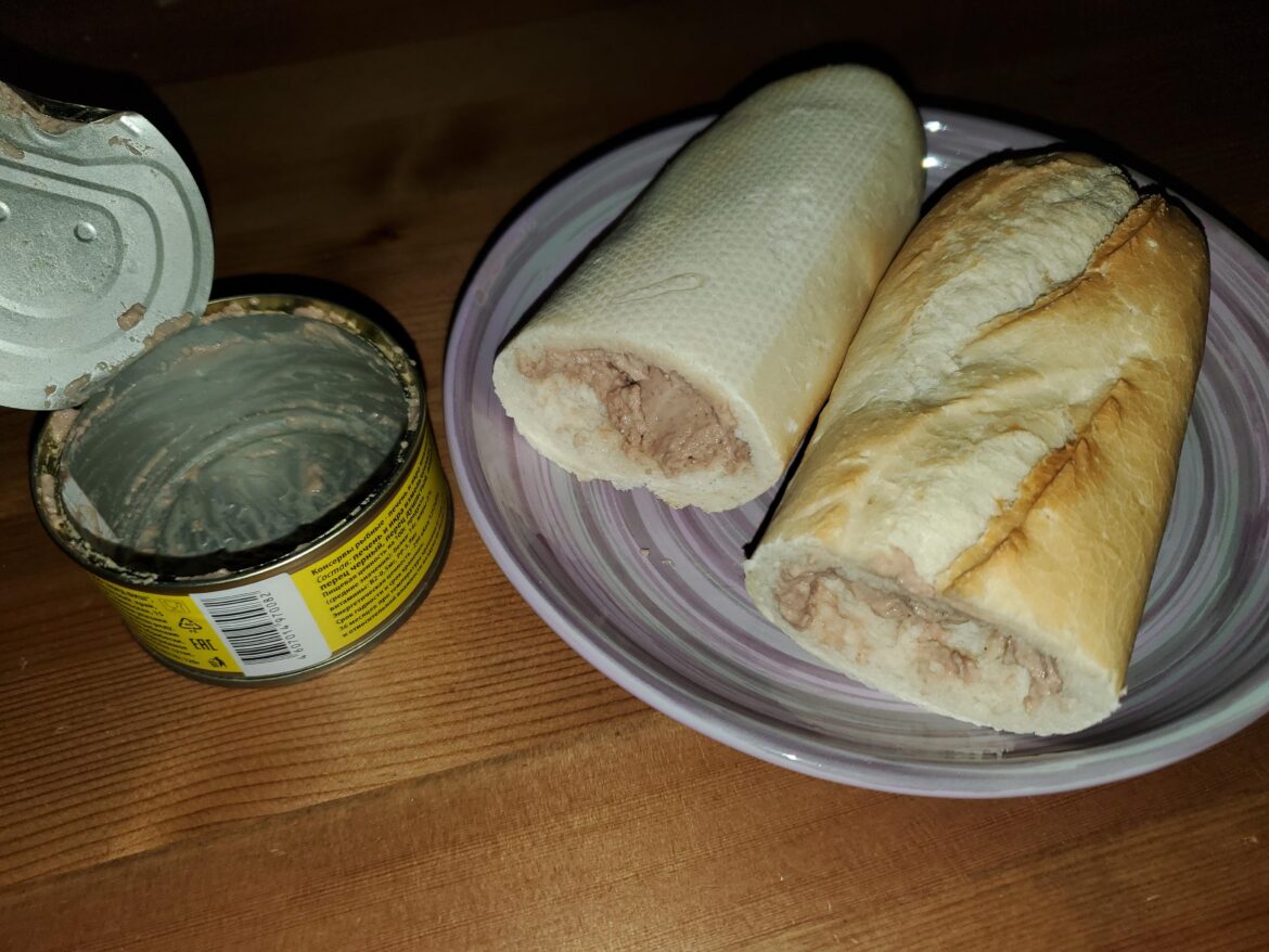A mini baguette hollowed out with a knife and stuffed with a whole can of fish liver