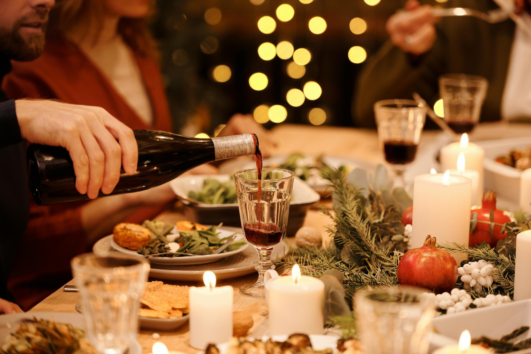 People sit together at the dinner table pouring wine at the traditional French Christmas Eve meal