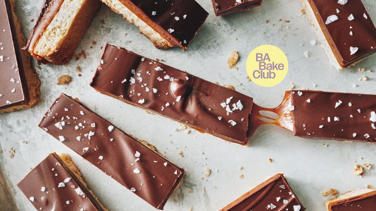 Bars of chocolate caramel and shortbread on a baking sheet topped with flakey salt.