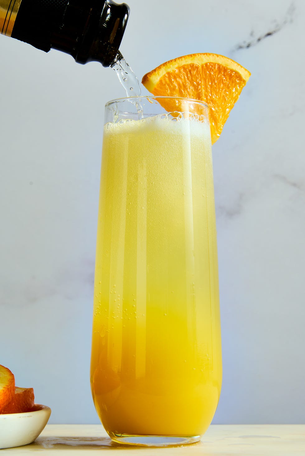 orange juice and champagne in a flute garnished with an orange wedge