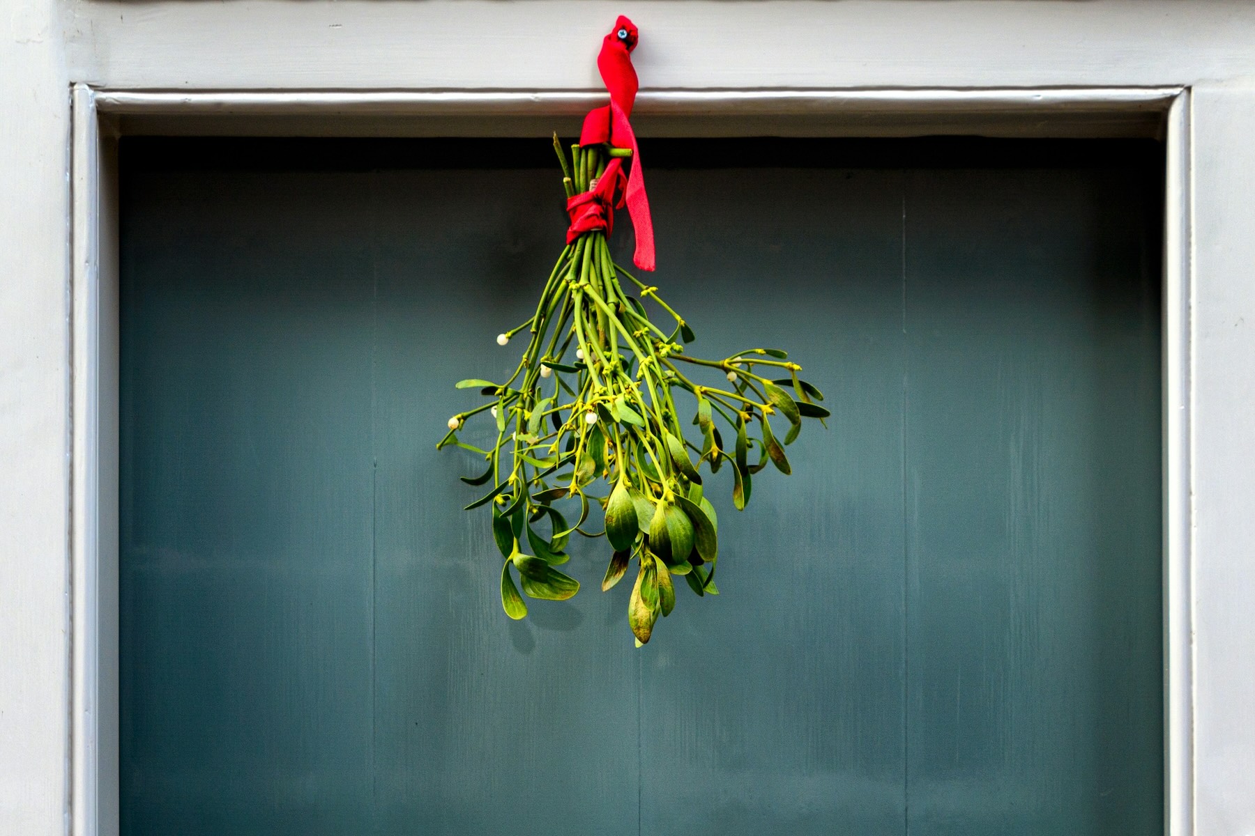 Christmas mistletoe hangs by red ribbon above the doorway of a French home