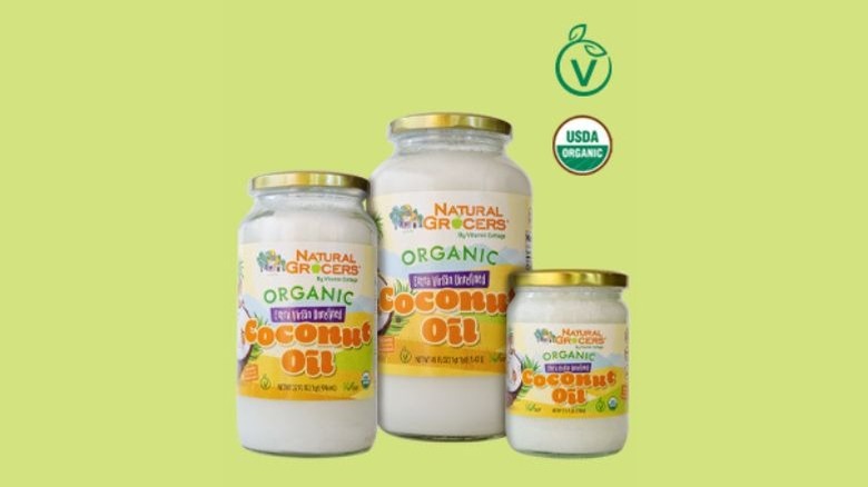 Three bottles of Natural Grocers Organic Extra Virgin Coconut Oil in a green backrgound