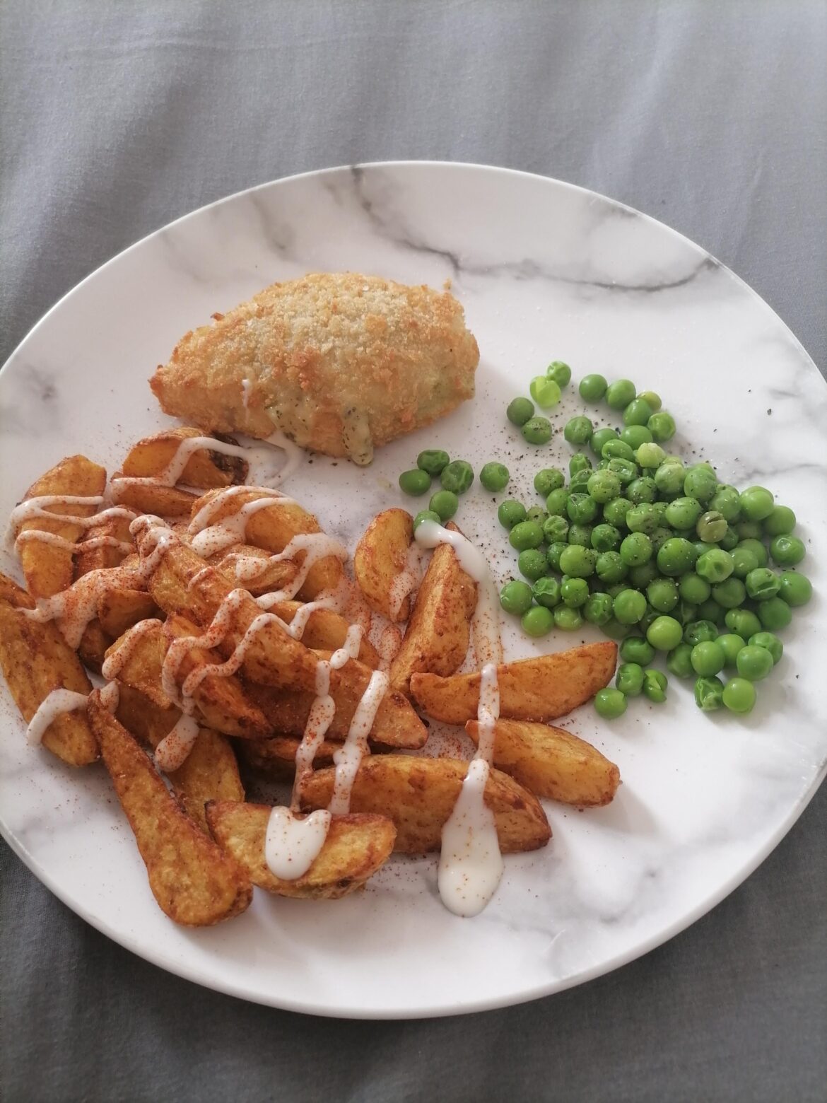Chicken Kiev with potato wedges, garlic mayo, chilli powder, and peas