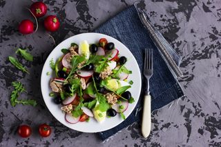 Nicoise salad with tuna, egg, cherry tomatoes and black olives on grey dark background. French cuisine. Top view, copy space (Nicoise salad with tuna, egg, cherry tomatoes and black olives on grey dark background. French cuisine. Top view, copy space,