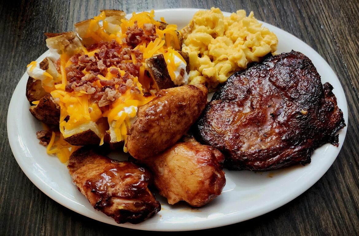 Barbecue pork steak, wings, loaded baked potato, and macaroni and cheese.