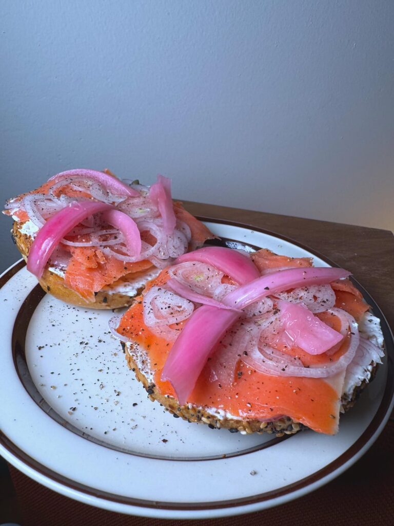 Homemade lox on everything bagel with whipped cream cheese, capers, shallots and pickled red onions and more shallots..