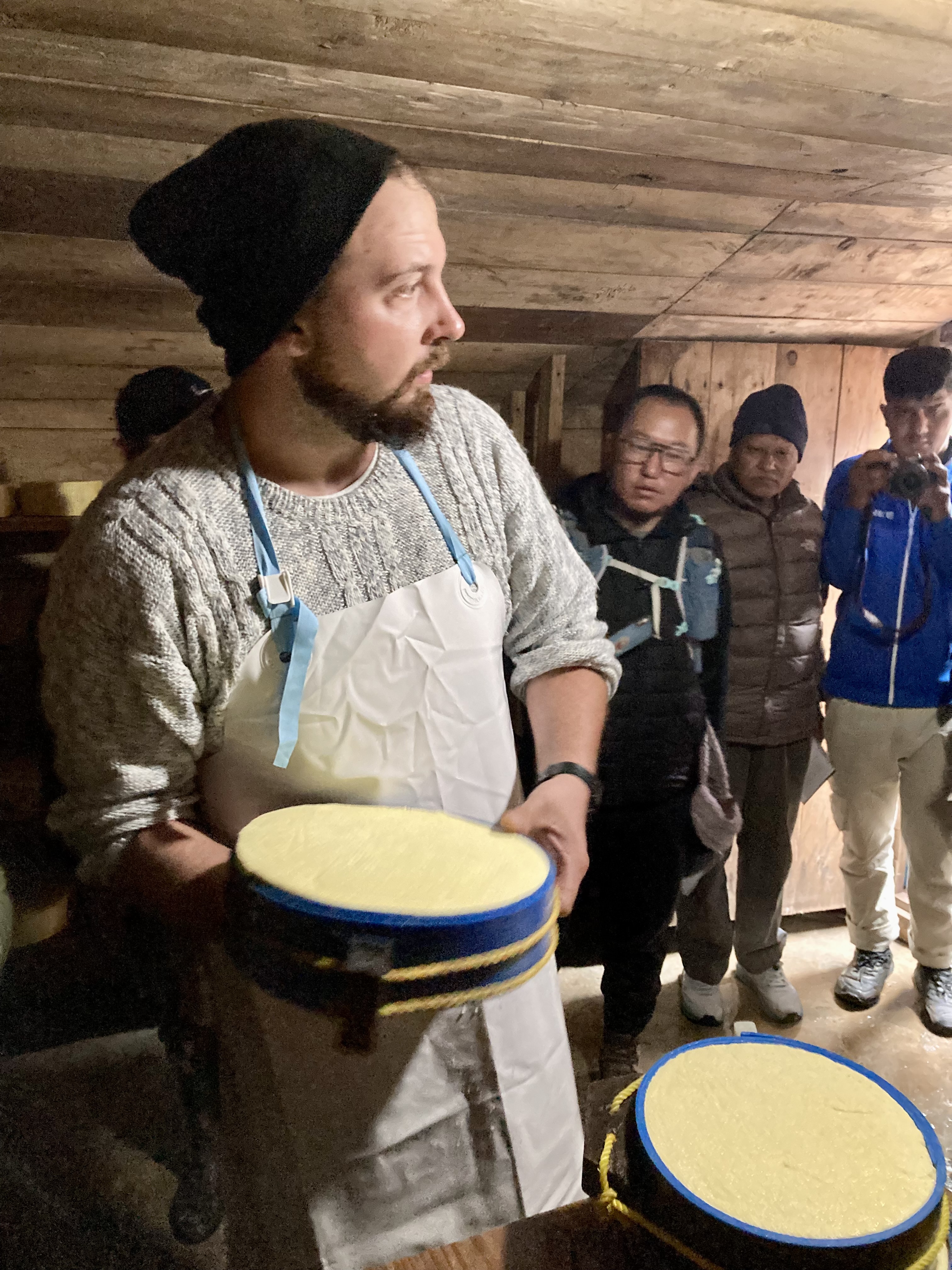 Cheesemaker holding a wheel of cheese.