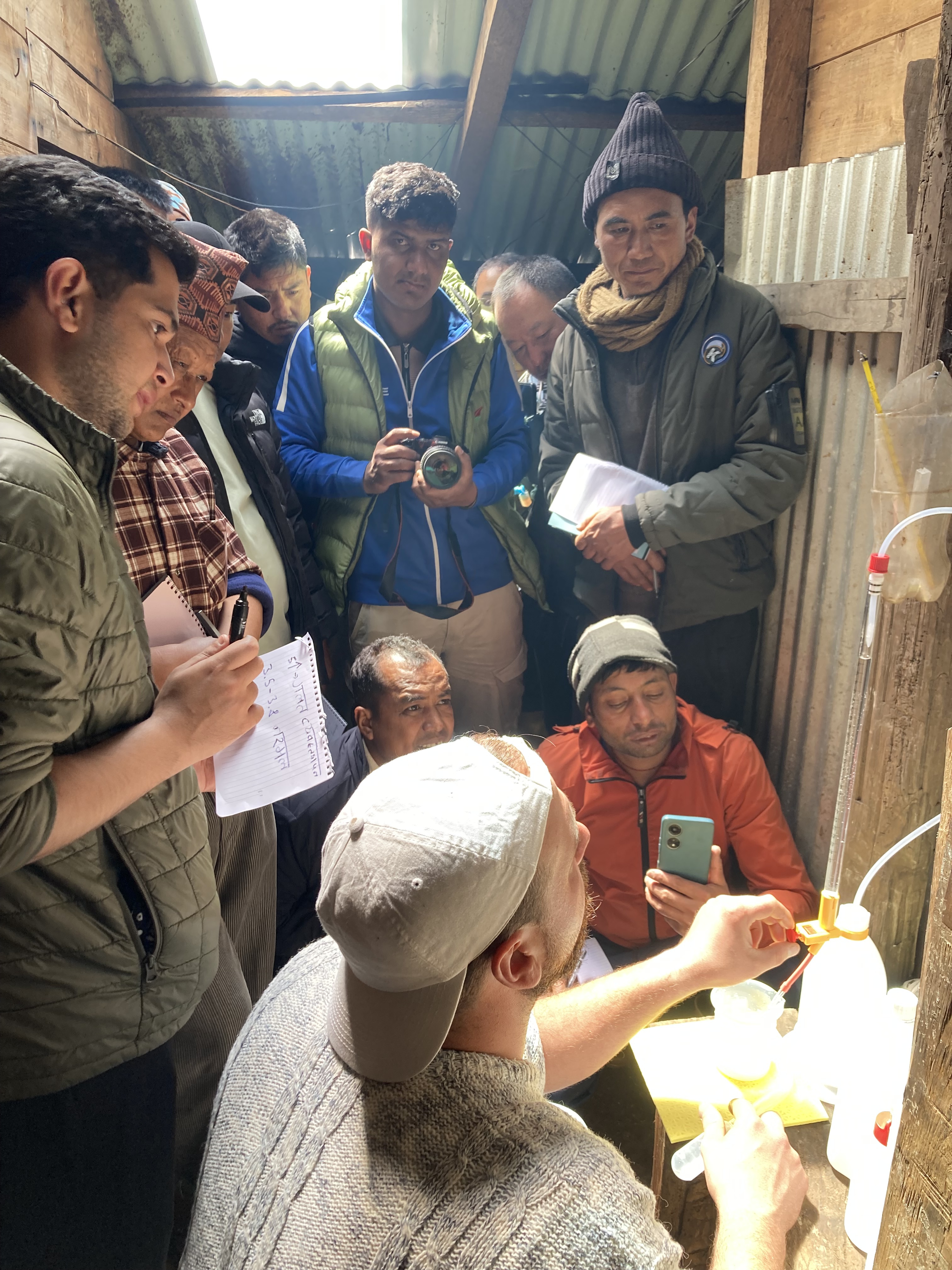 A cheesemaker and a group of people observing a cheesemaking process.