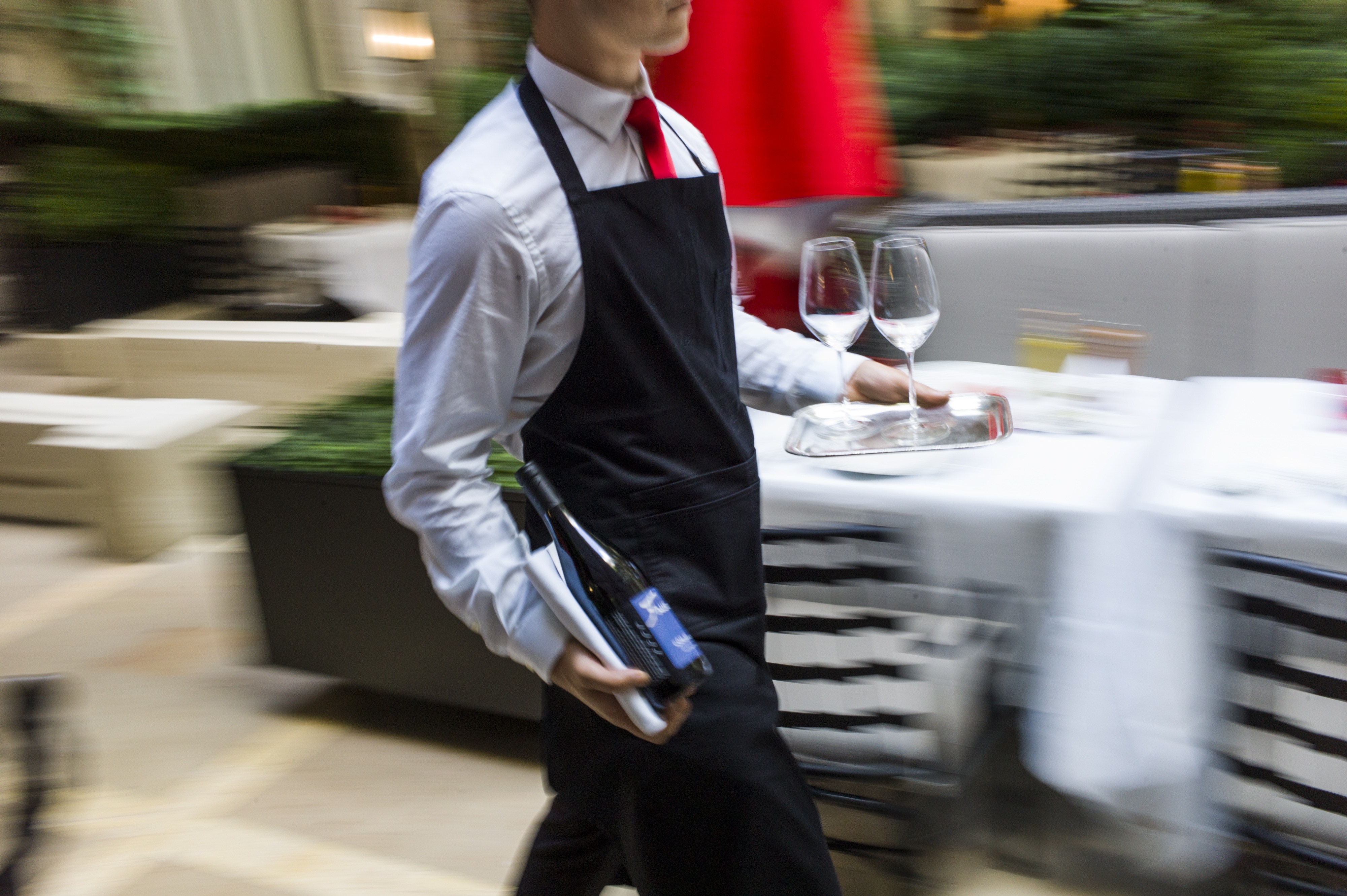 Waiter carrying wine and glasses at the Plaza Athenee hotel in Paris.