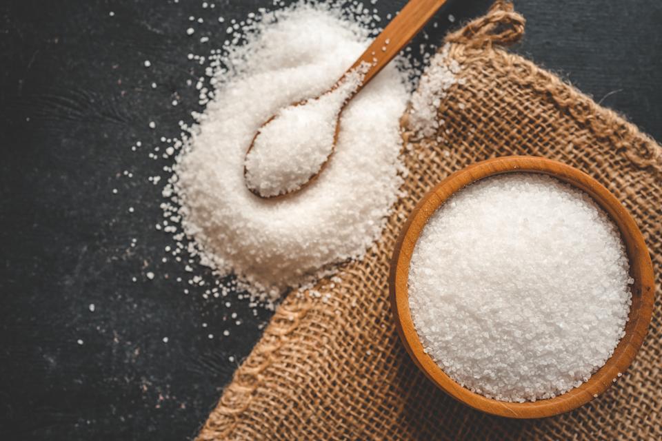 Wooden bowl and spoon with salt, top view.